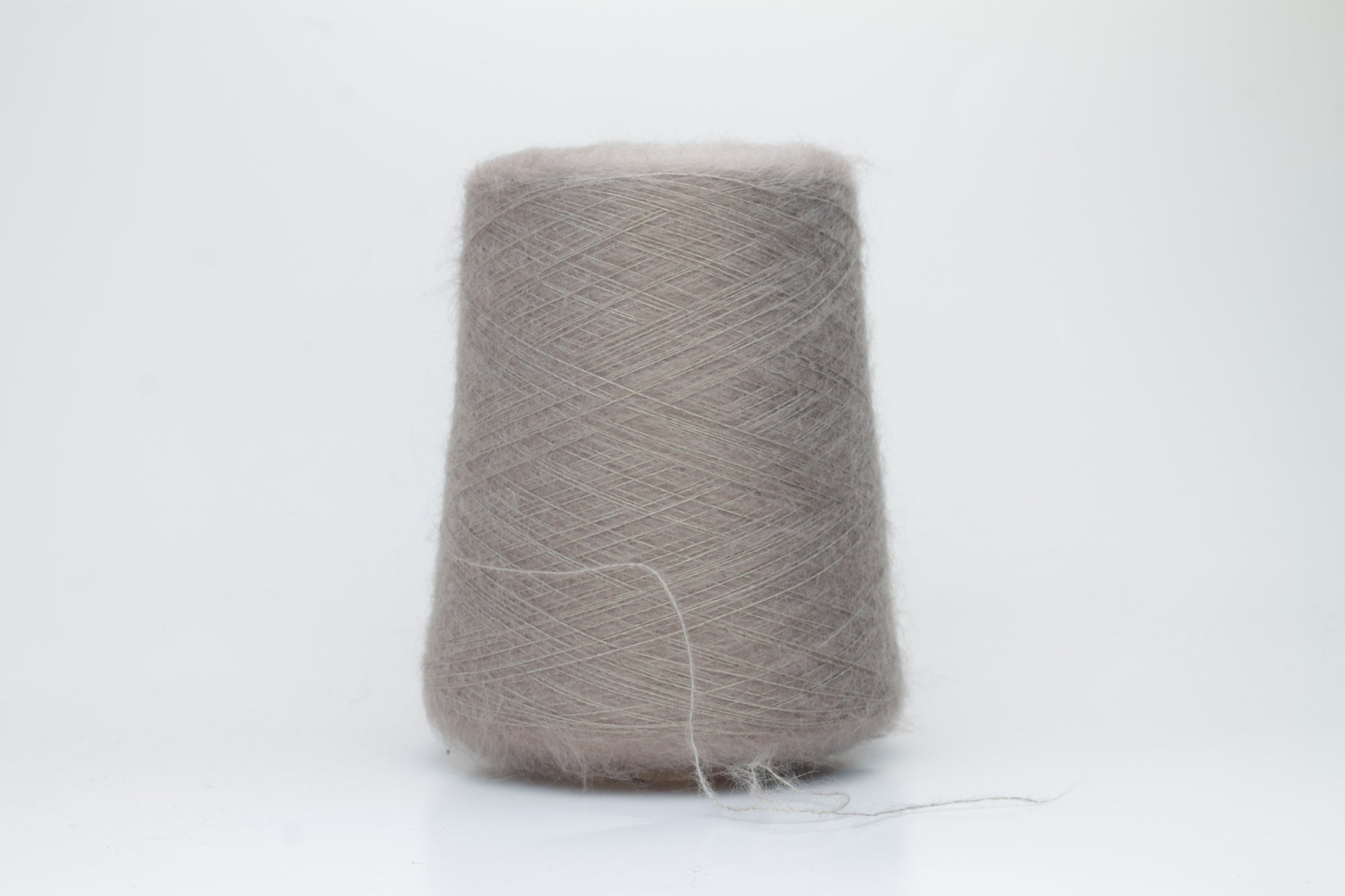 Close-up of fluffy Beige kid mohair and silk blend yarn, subtly lustrous with a soft halo, gently twisted into a fine, delicate thread.