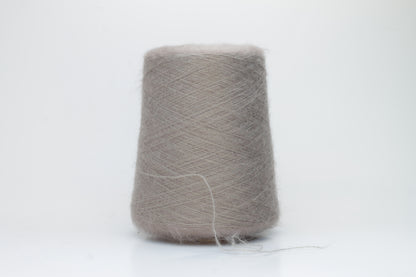 Close-up of fluffy Beige kid mohair and silk blend yarn, subtly lustrous with a soft halo, gently twisted into a fine, delicate thread.