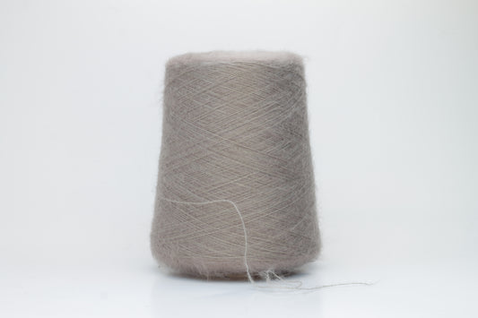 Close-up of fluffy Beige kid mohair and silk blend yarn, subtly lustrous with a soft halo, gently twisted into a fine, delicate thread.
