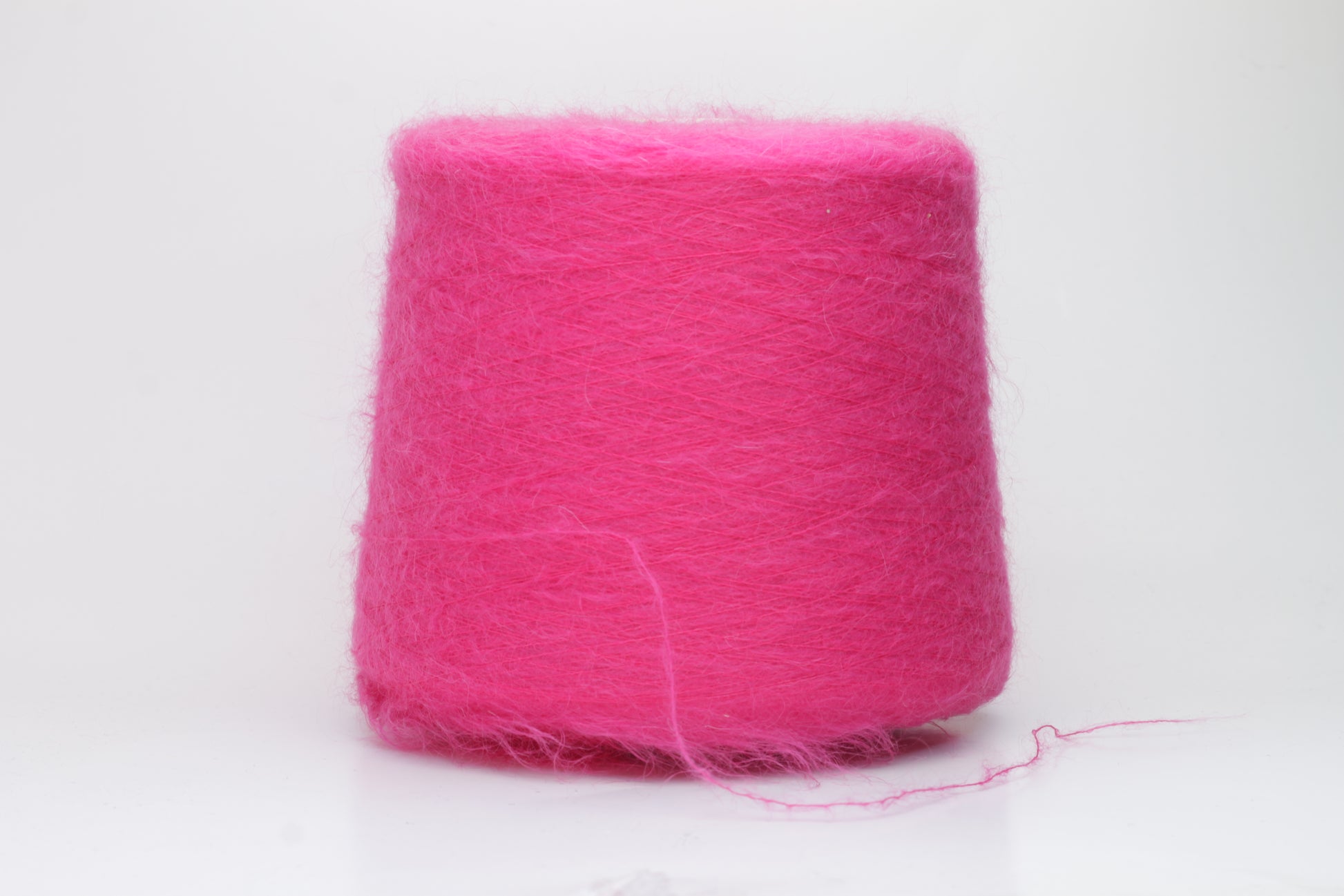 Close-up view of SuperKidMohair yarn in Fuxia, showcasing its fluffy texture and slightly twisted ply structure with subtle sheen.