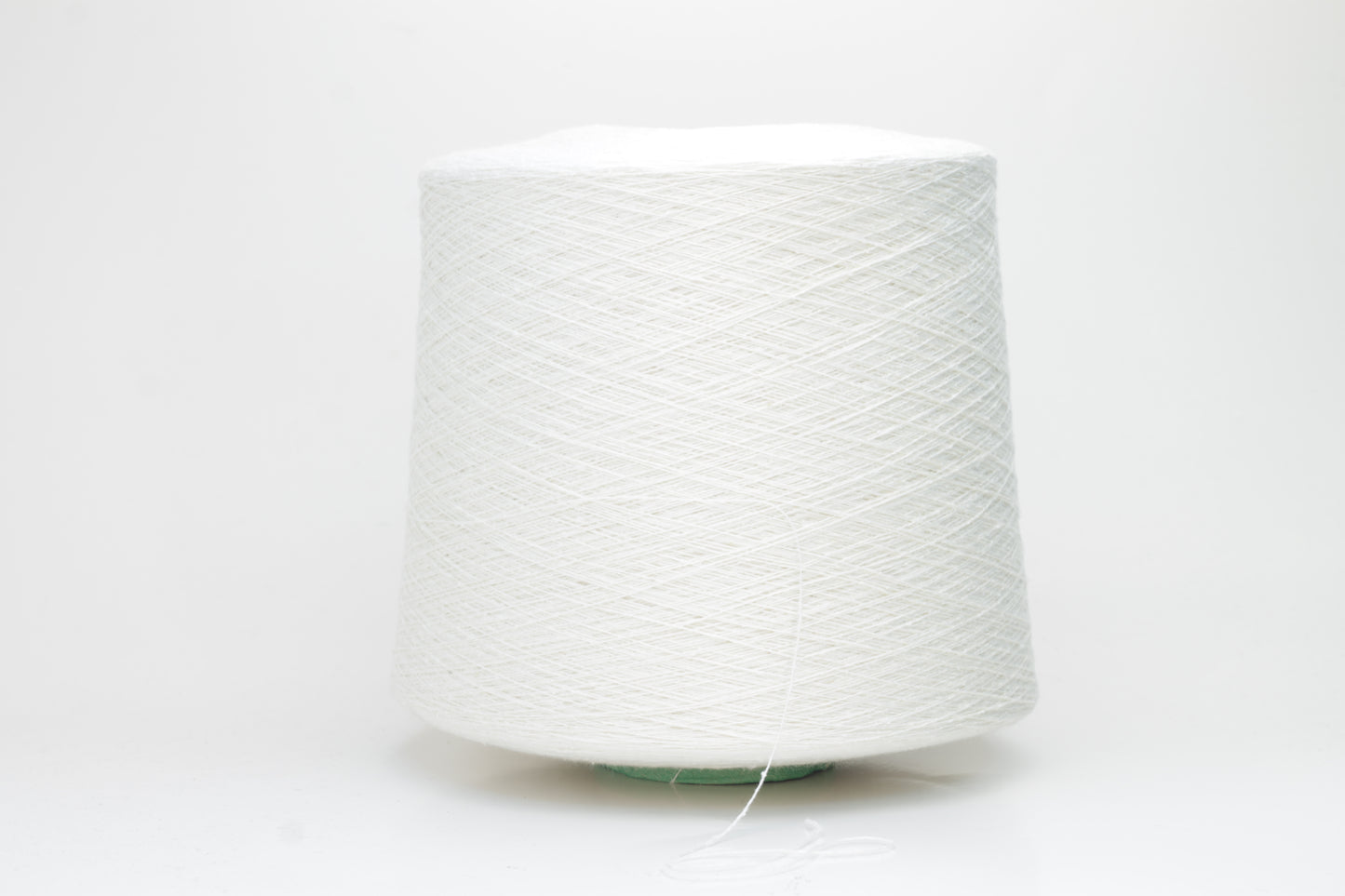 Close-up of softly textured, matte off-white bourette silk yarn. Shows subtle slubs and irregular spun threads in a single ply.
