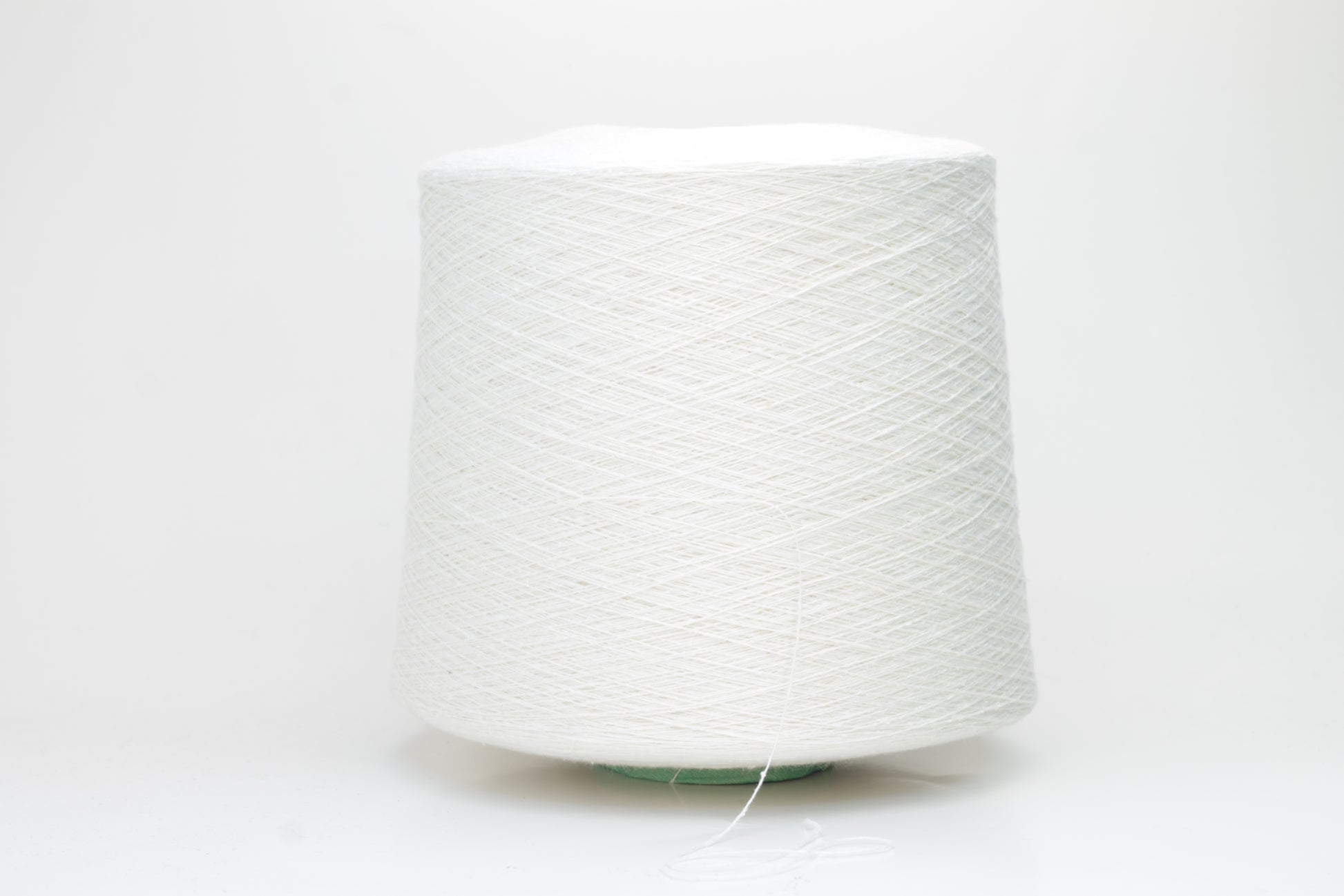 Close-up of softly textured, matte off-white bourette silk yarn. Shows subtle slubs and irregular spun threads in a single ply.