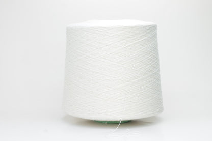 Close-up of softly textured, matte off-white bourette silk yarn. Shows subtle slubs and irregular spun threads in a single ply.