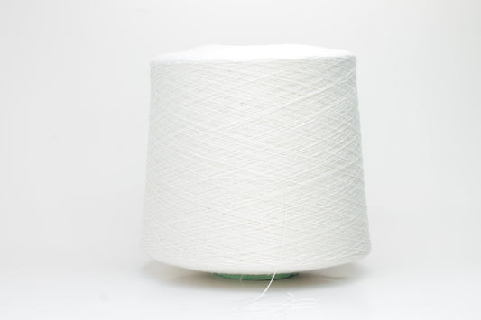 Close-up of softly textured, matte off-white bourette silk yarn. Shows subtle slubs and irregular spun threads in a single ply.