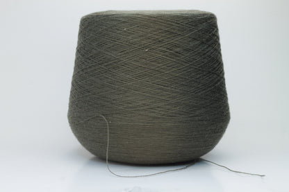 Close-up shot of a vibrant green Merino 100% Cashwool yarn skein. The yarn features a tight, dense ply twist and a subtle sheen, with visible individual strands creating a rich, textured effect.