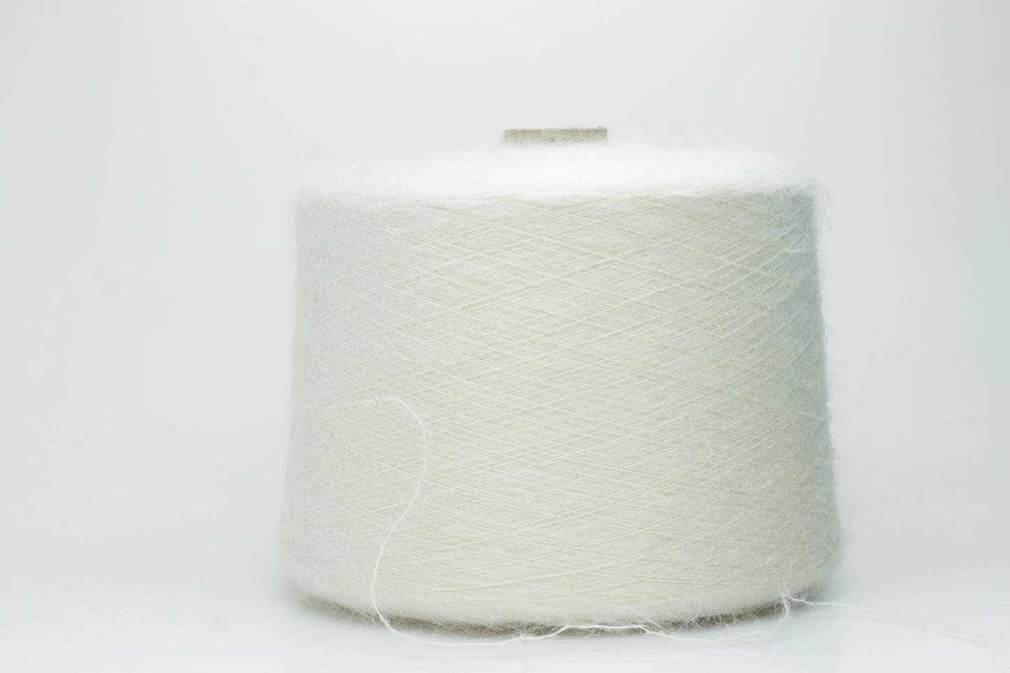Close-up of fine white Kid Mohair and Silk yarn, exhibiting a soft, ethereal halo and subtle luminous sheen, gently twisted.