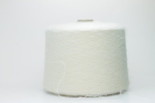 Close-up of fine white Kid Mohair and Silk yarn, exhibiting a soft, ethereal halo and subtle luminous sheen, gently twisted.
