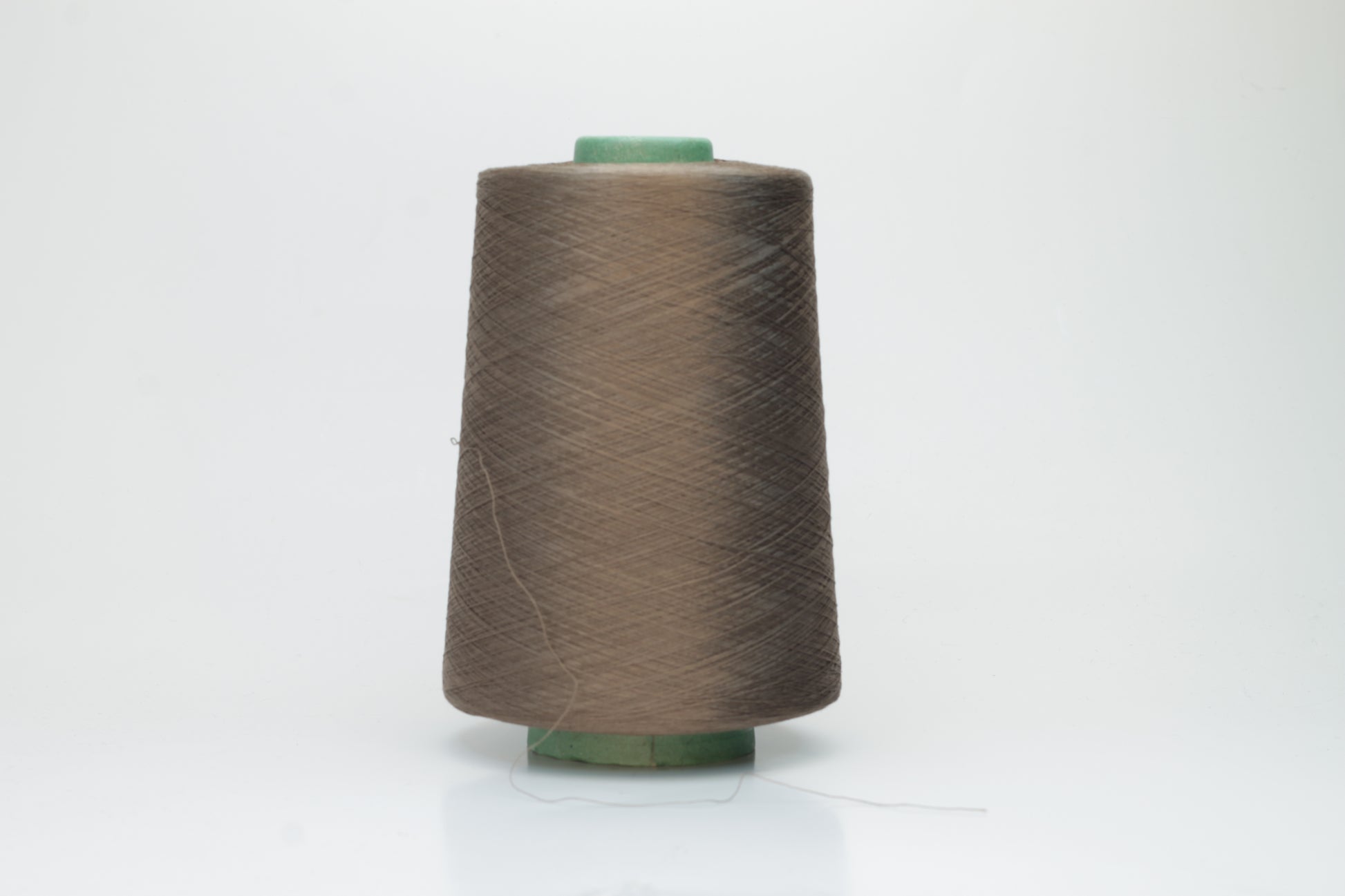Finely spun, single-ply silk yarn in a deep, rich cacao brown, exhibiting a smooth, tight twist and brilliant, natural sheen.