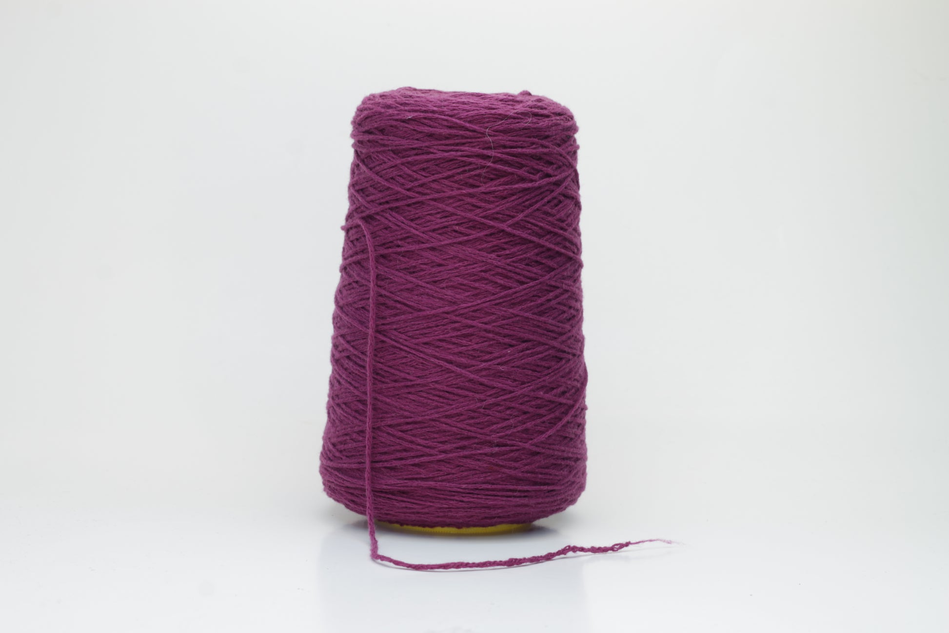 Close-up of soft, lustrous pure cashmere yarn, gently twisted, revealing a rich, deep anemone purple with a subtle, velvety halo.