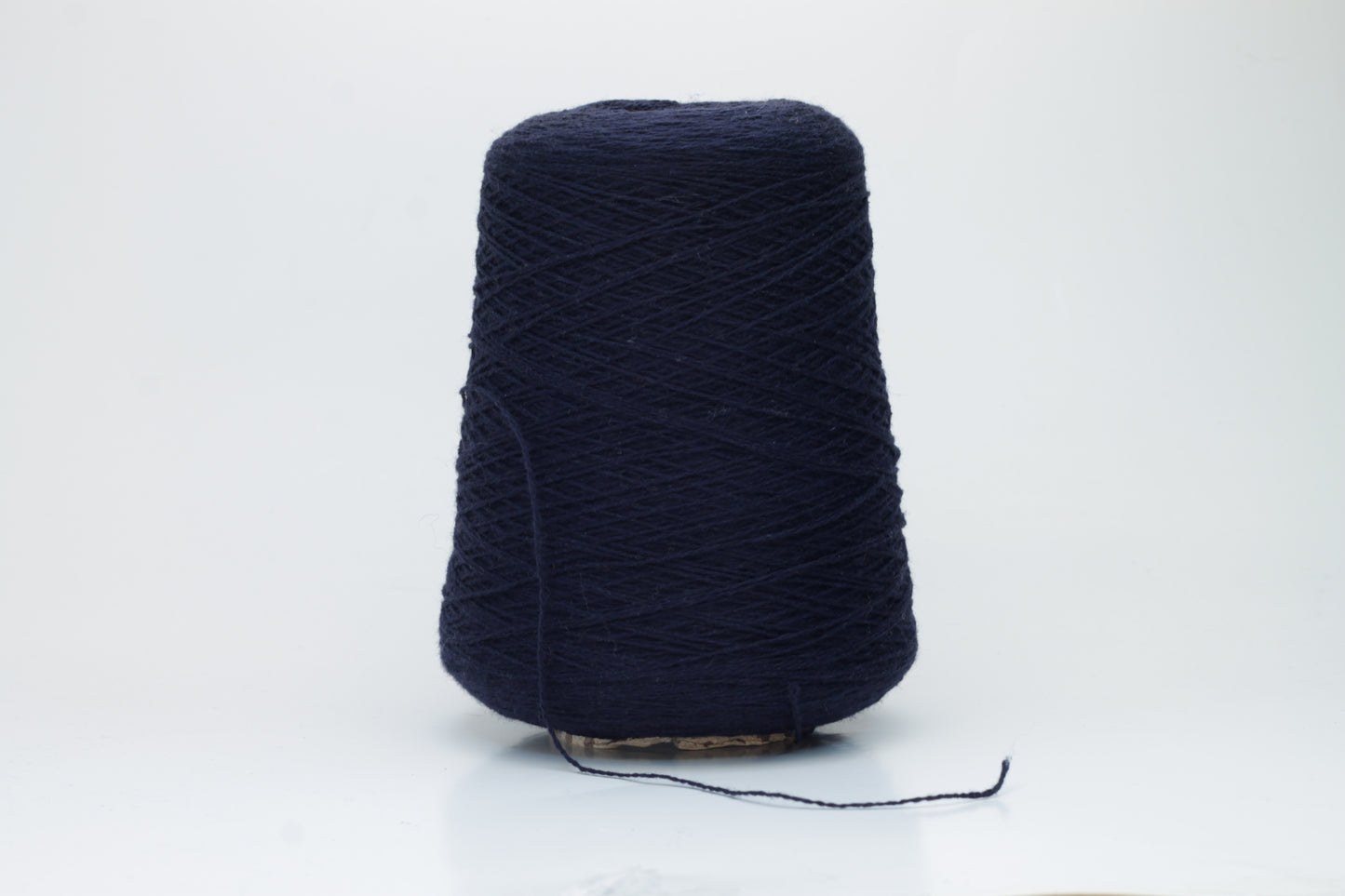 A tightly spun two-ply yarn, rich navy blue, made from exceptionally soft, fine cashmere fibers with a slight halo, presented as a graceful hank.
