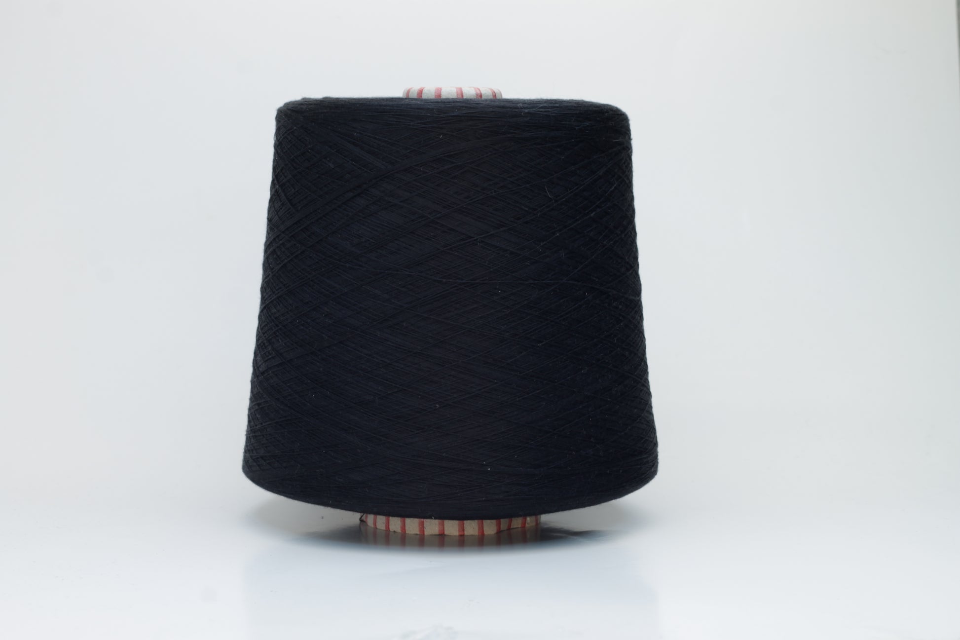 Close-up of luxurious black 100% silk yarn, tightly plied with a smooth, high-luster surface reflecting light. It has a deep, true black color, wound evenly on a cone.