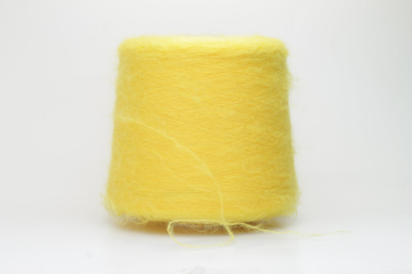 Close-up shot of vibrant yellow SuperKidMohair yarn showing a tight ply twist and soft, fluffy texture. The fibers exhibit a subtle sheen with excellent color depth.