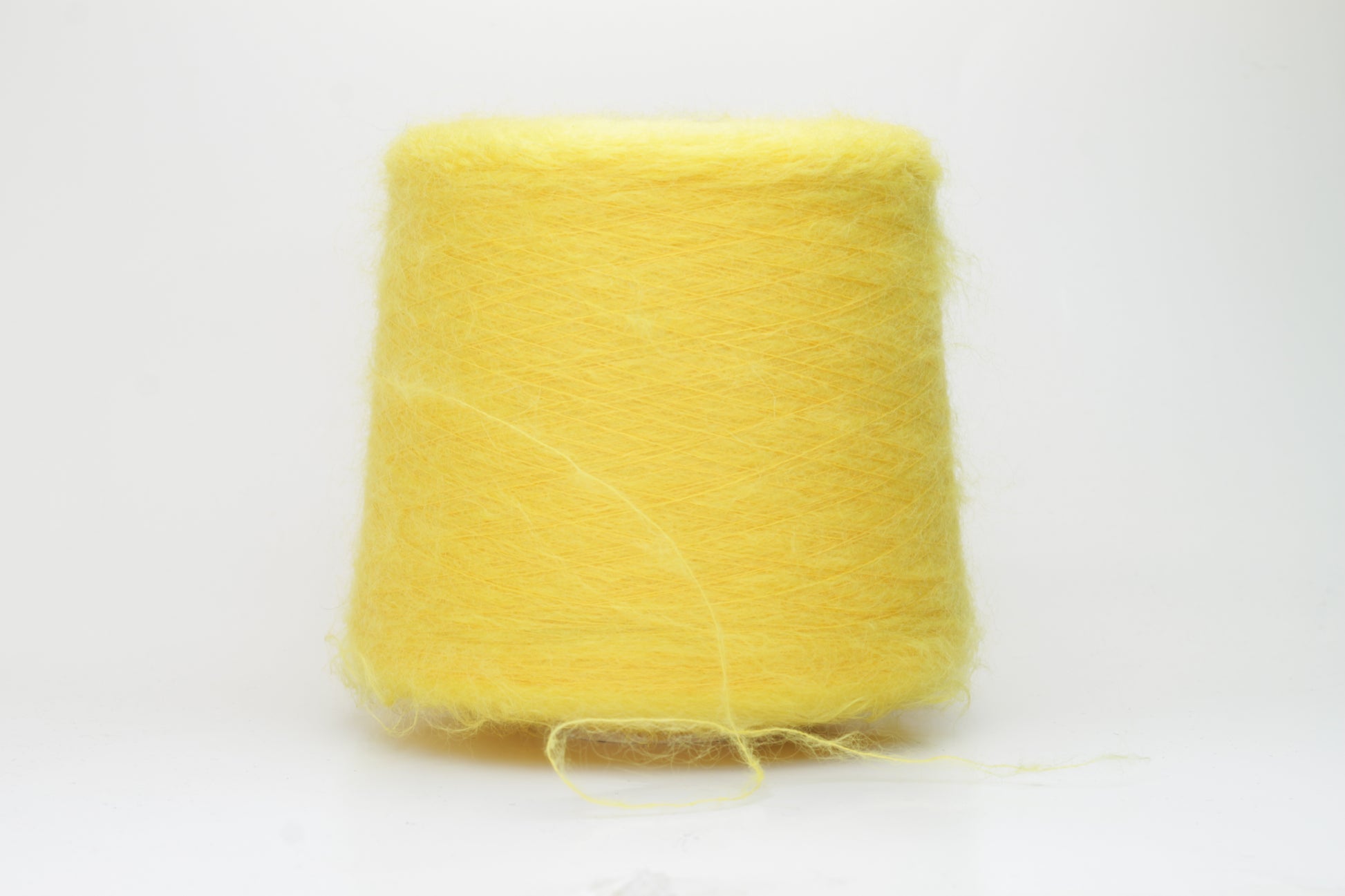 Close-up shot of vibrant yellow SuperKidMohair yarn showing a tight ply twist and soft, fluffy texture. The fibers exhibit a subtle sheen with excellent color depth.