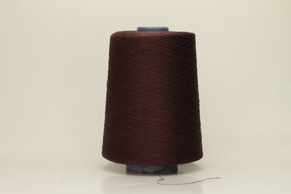 Close-up of a deep, rich espresso brown silk yarn wound in a neat cake, showcasing its smooth, lustrous surface and fine, even ply twist. The individual strands reflect light softly.