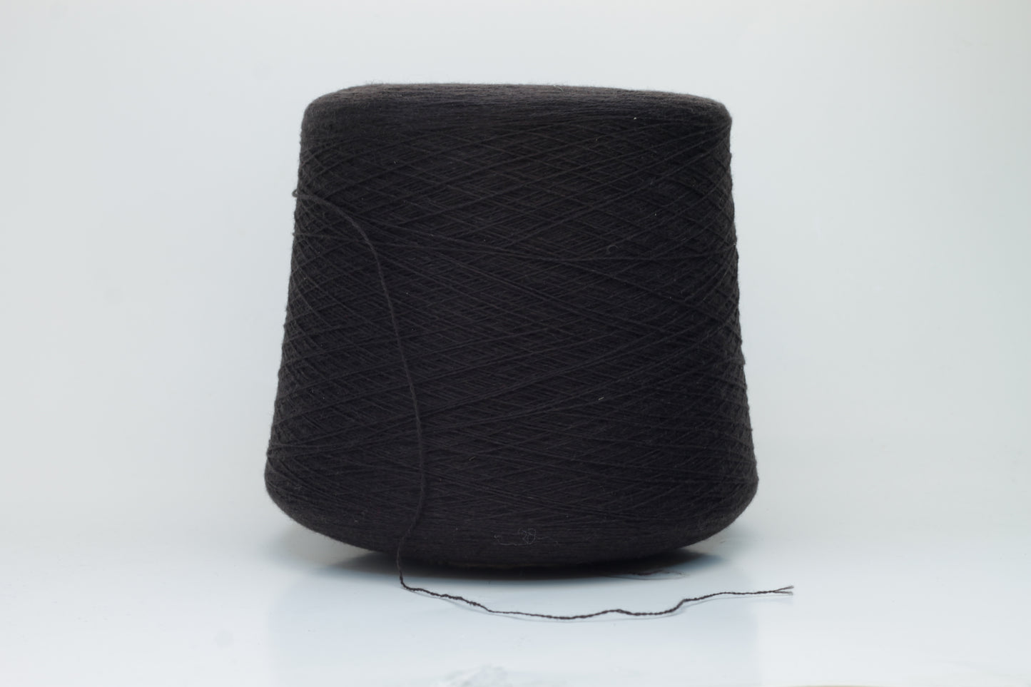 Close-up of a two-ply dark brown cashmere yarn, softly twisted with a subtle sheen, displaying its deep rich hue and delicate fuzziness, ready for luxury crafting.