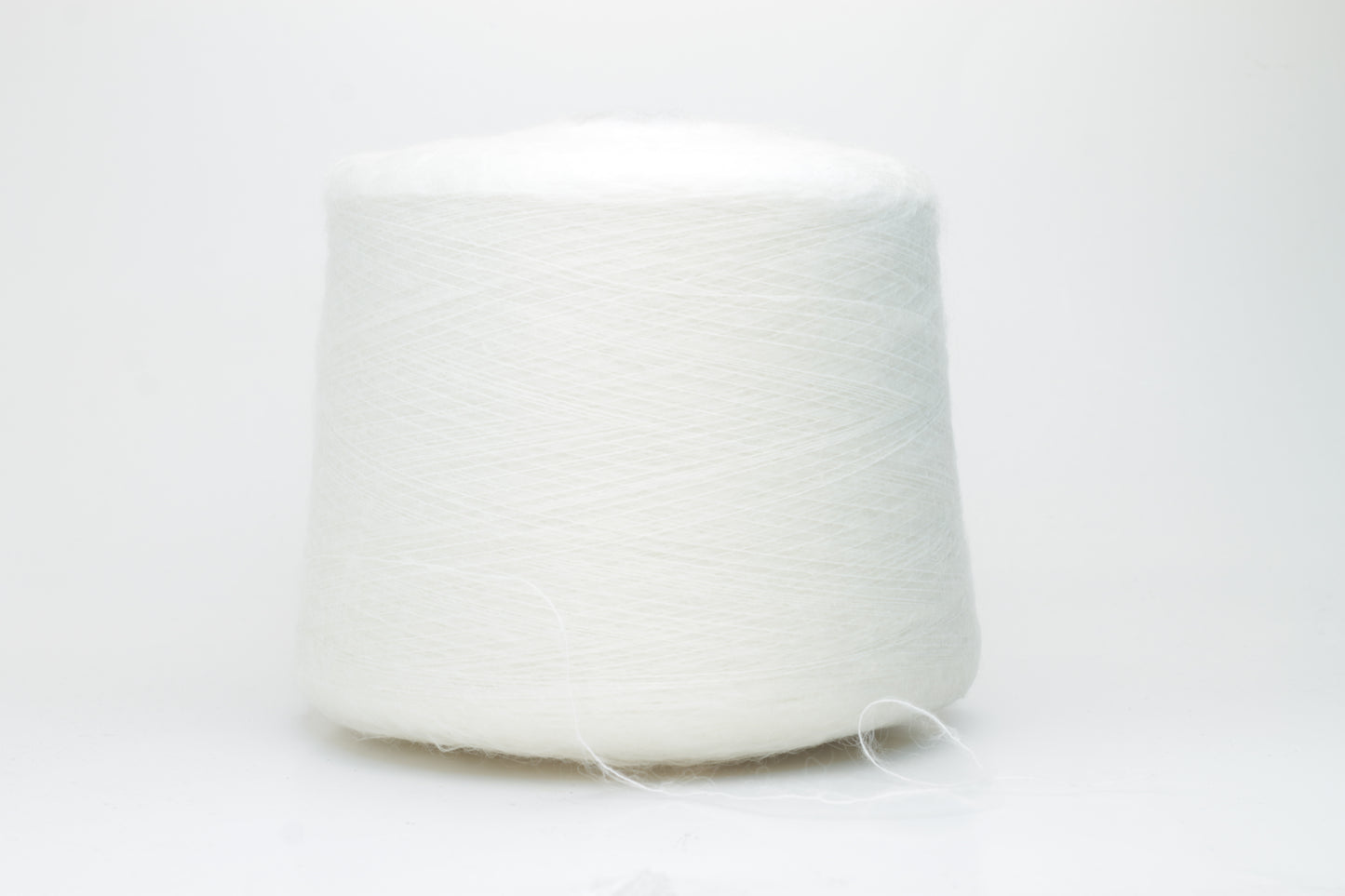 Close-up view of SuperKidMohair yarn in Aurora White color, showcasing its fluffy texture and subtle sheen. The yarn exhibits a smooth ply twist with a rich color depth.