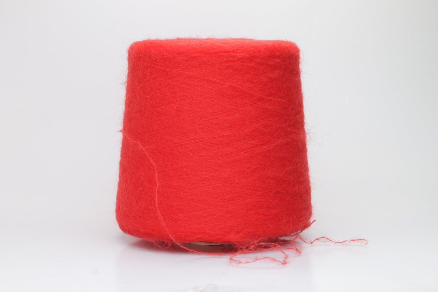 Close-up view of vibrant red SuperKidMohair yarn featuring a dense, fluffy pile with subtle sheen. The ply twist is evident in the slightly twisted structure, creating a soft and luxurious tactile experience.