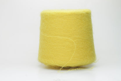 Close-up view of vibrant yellow SuperKidMohair yarn in a loose, fluffy ply twist. The yarn exhibits significant sheen and fluffiness, with distinct individual fibers visible.