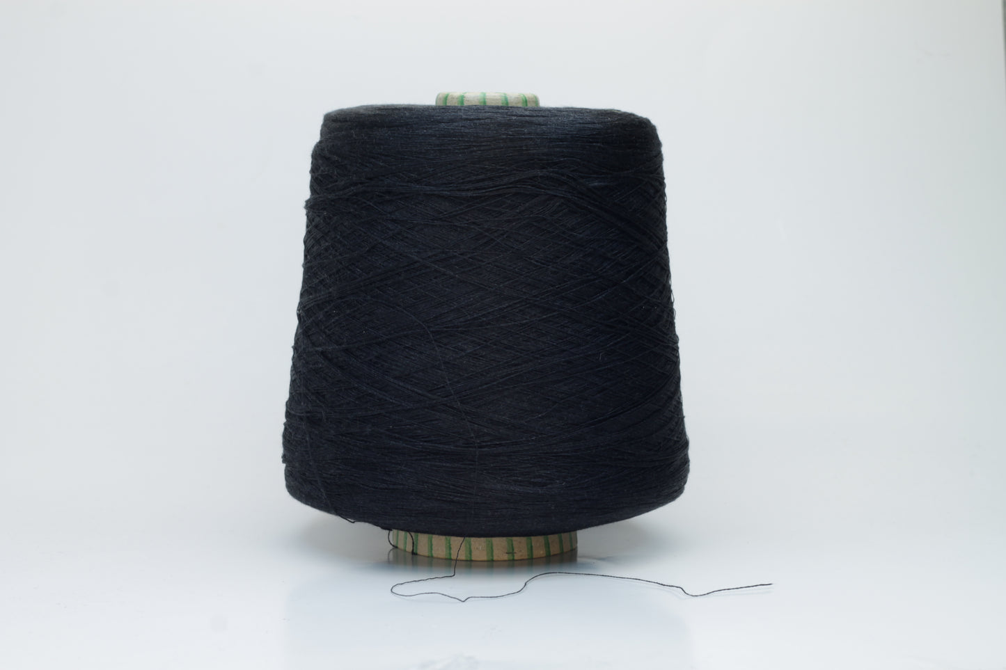 Spool of rich, deep black silk yarn, showcasing its fine, smooth plies and radiant, natural luster against a soft background.