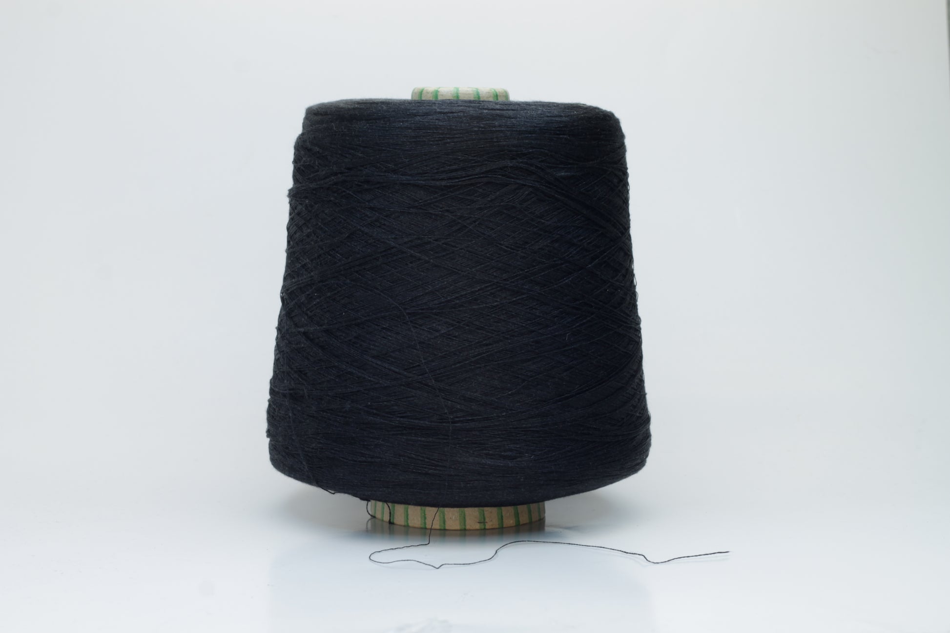 Spool of rich, deep black silk yarn, showcasing its fine, smooth plies and radiant, natural luster against a soft background.