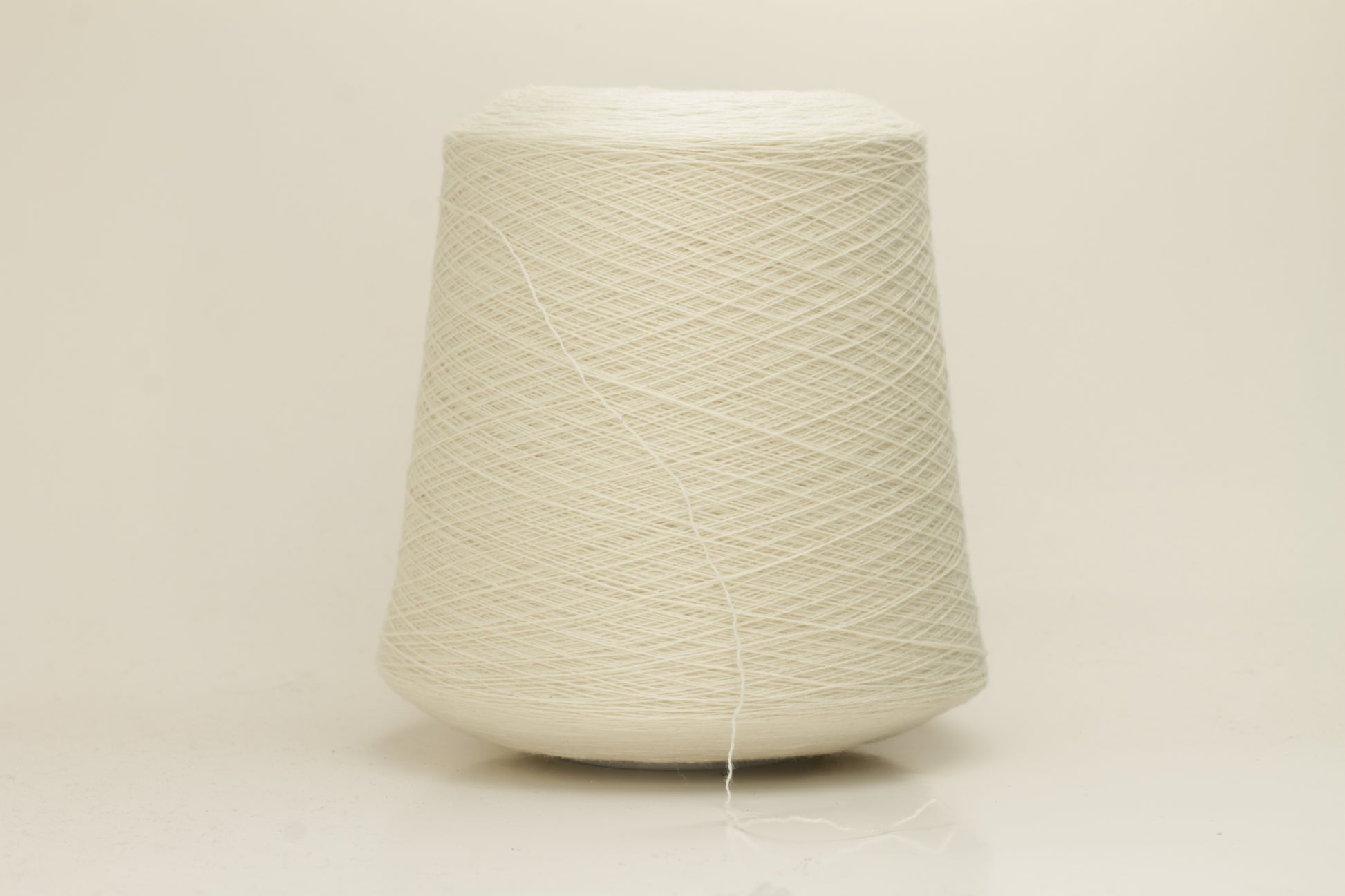 Close-up of a skein of pristine Ice White 100% cashmere yarn, showcasing its fine, evenly plied two-ply structure and delicate, soft halo.