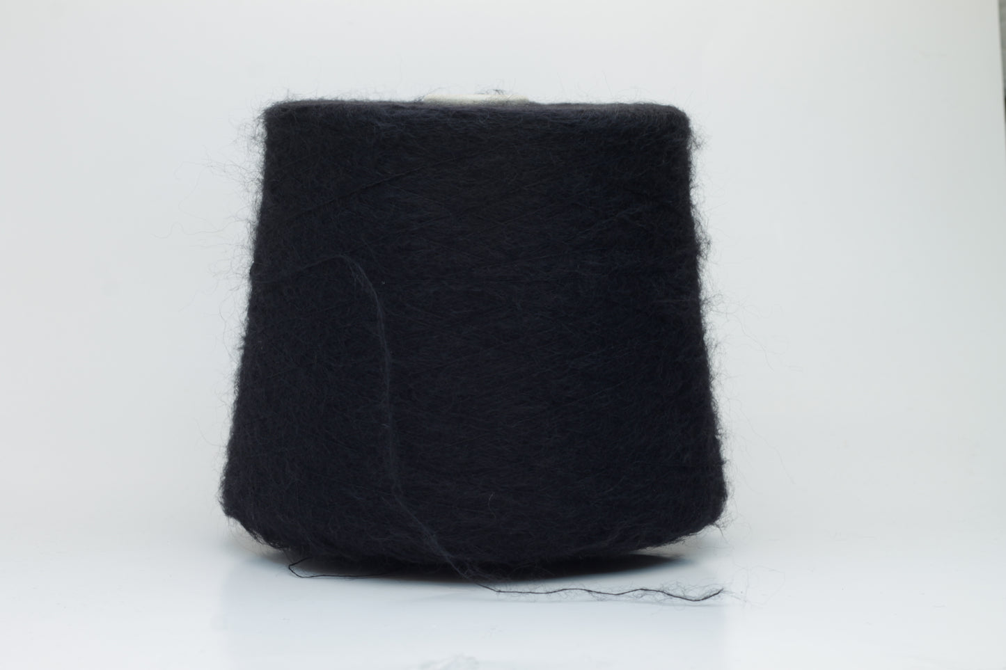 Close-up shot of the Black SuperKidMohair yarn, showcasing its dense ply twist and subtle sheen. The fibers appear fluffy and richly colored, creating a luxurious tactile impression.