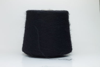 Close-up shot of the Black SuperKidMohair yarn, showcasing its dense ply twist and subtle sheen. The fibers appear fluffy and richly colored, creating a luxurious tactile impression.
