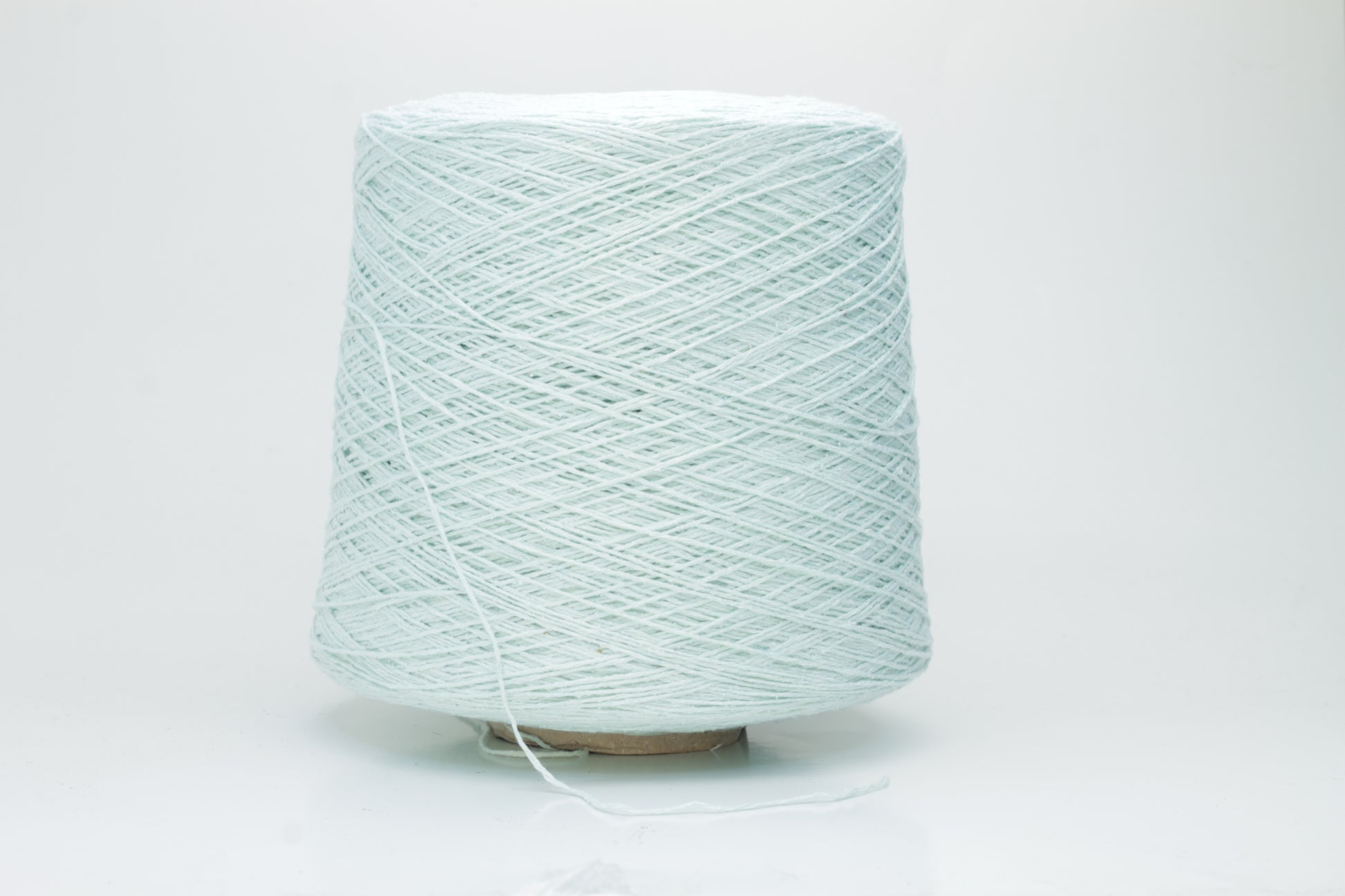 Close-up of a skein of unspun, single-ply bourette silk yarn. It has a natural, slightly textured, slubbed surface with a soft matte sheen in a serene acqua blue-green hue.