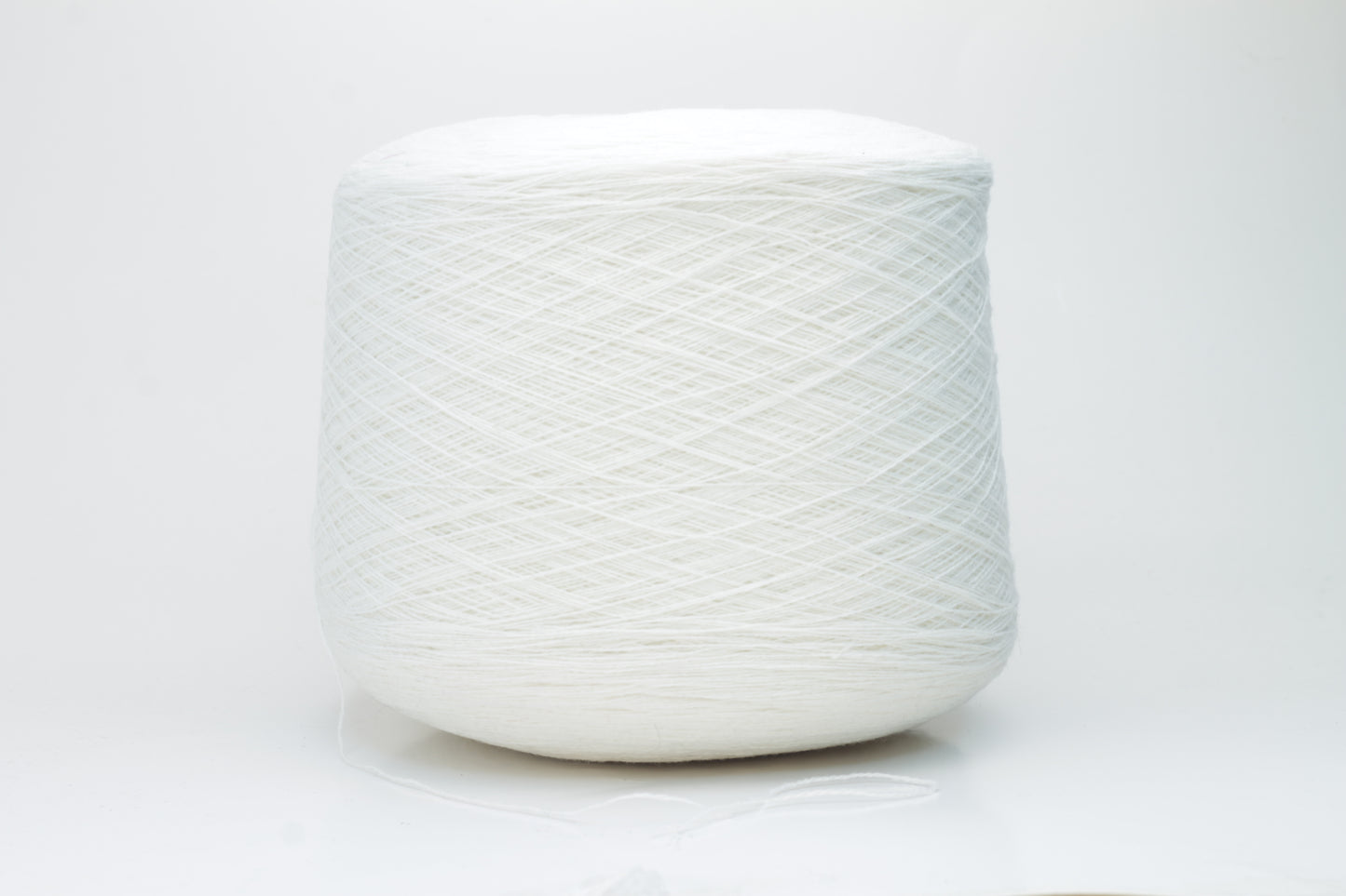 Close-up of a pristine white, two-ply cashmere yarn ball, subtly glowing with a luxurious, fine-fibered halo.