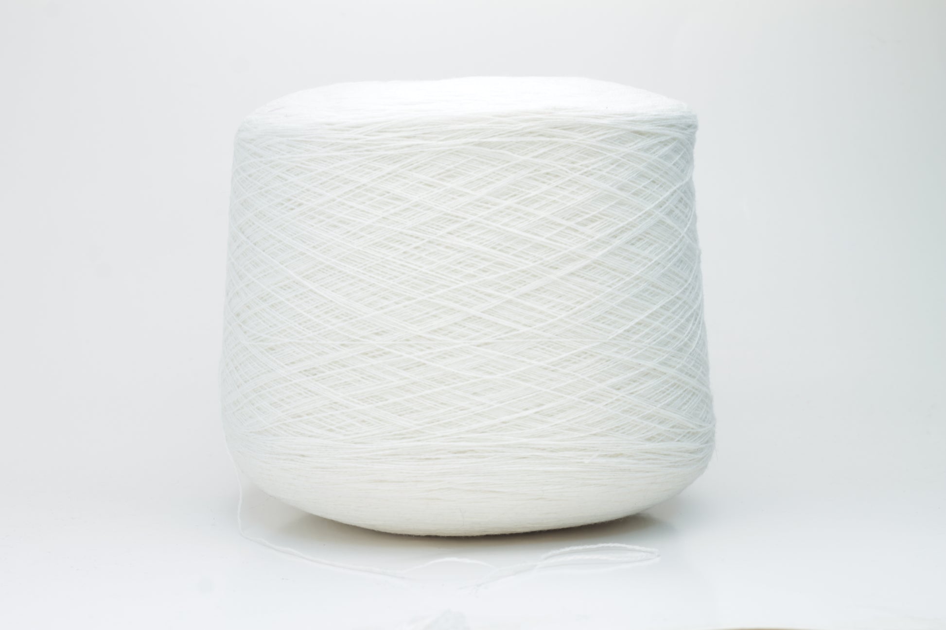 Close-up of a pristine white, two-ply cashmere yarn ball, subtly glowing with a luxurious, fine-fibered halo.