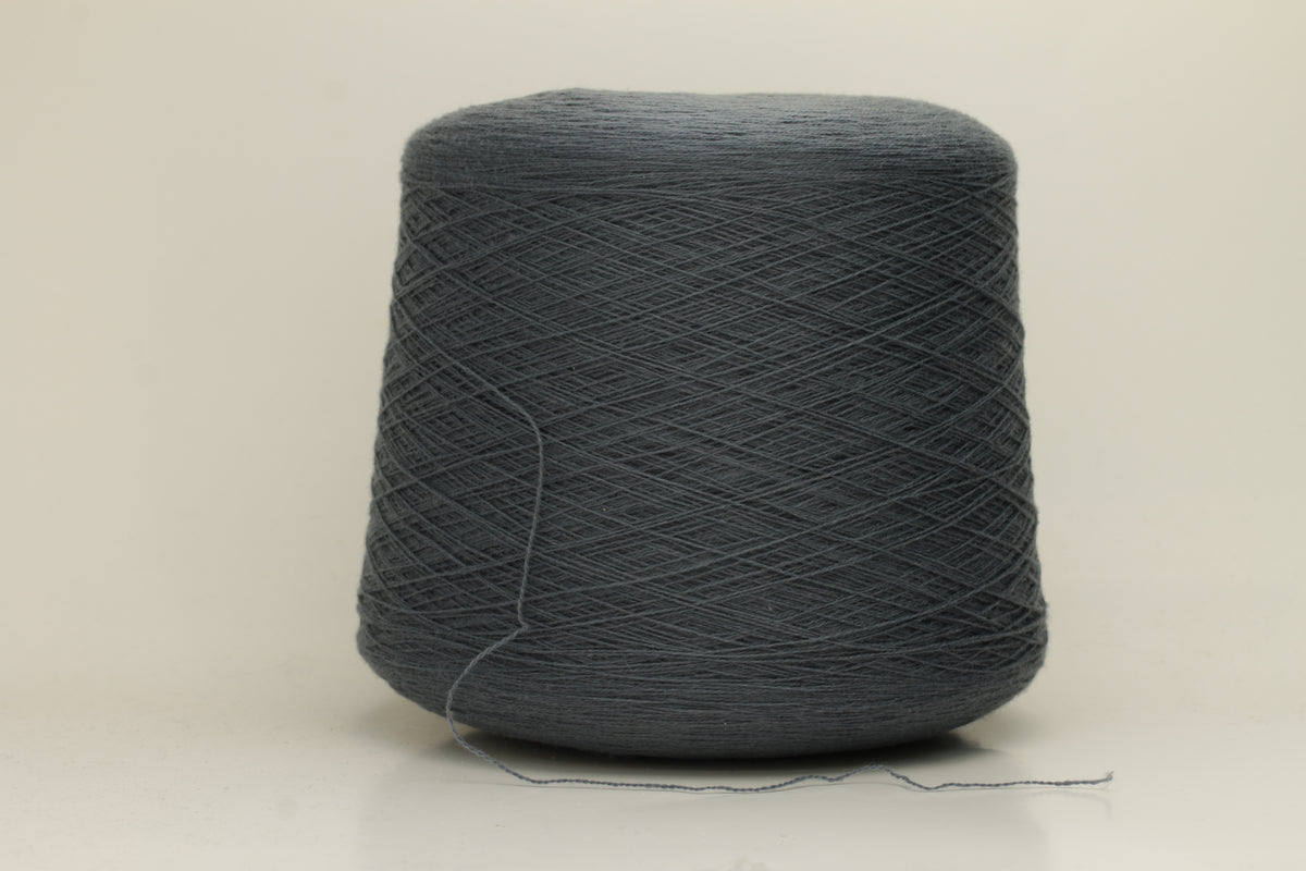 Close-up of a skein of dark, stormy blue-grey cashmere yarn with a subtle sheen. The fine, two-ply twist is visible, creating a smooth, incredibly soft thread structure that suggests luxurious warmth.
