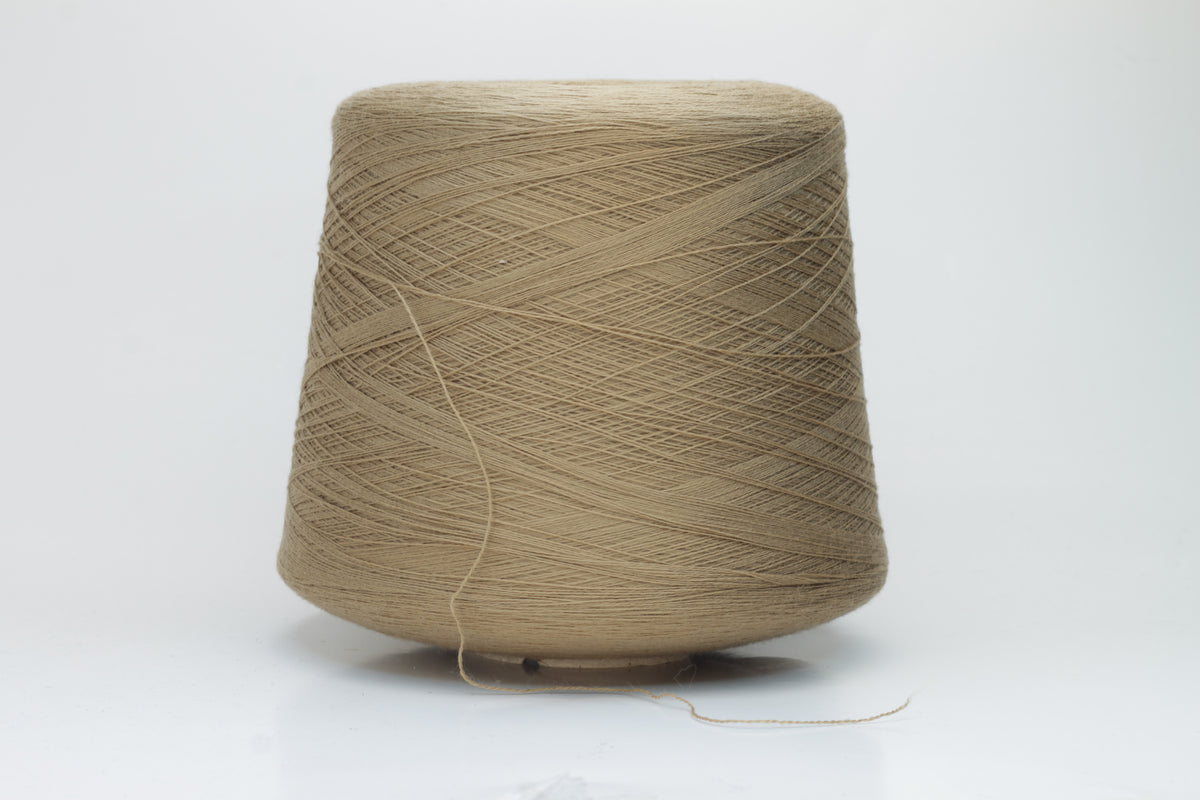 Close-up shot of a cone of creamy camel colored 100% merino yarn, showcasing the fine ply twist and subtle sheen of the fibers.