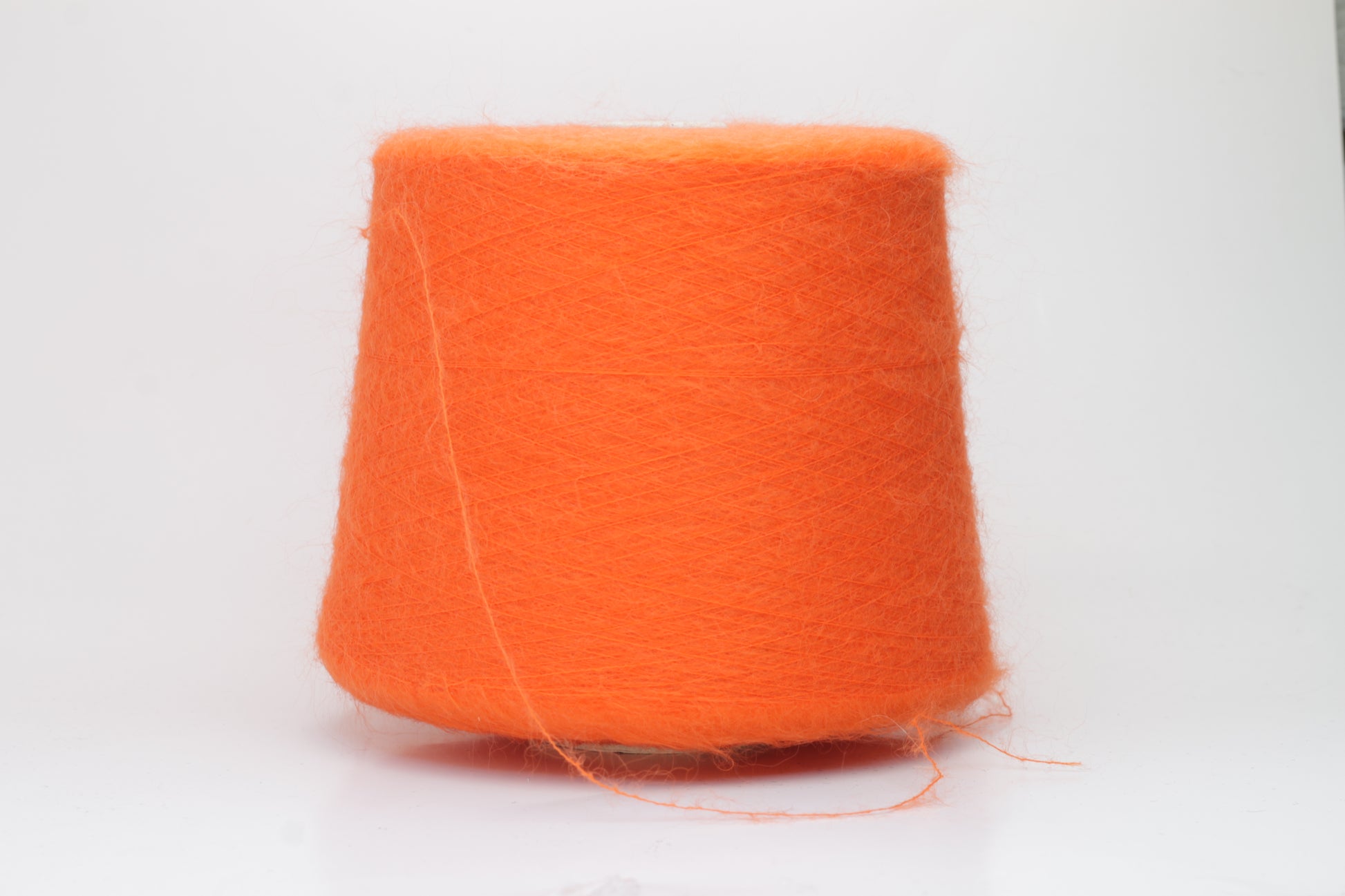Close-up shot of vibrant orange SuperKidMohair yarn, displaying a tight ply twist and a rich, fluffy texture with noticeable sheen.