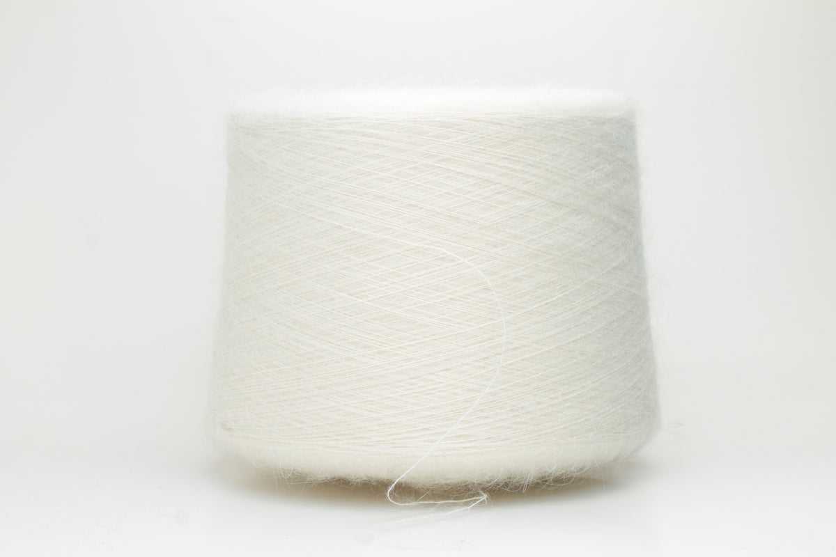 Close-up of pristine white SuperKidMohair Silk yarn, revealing its delicate halo, subtle sheen, and fine, even ply twist.