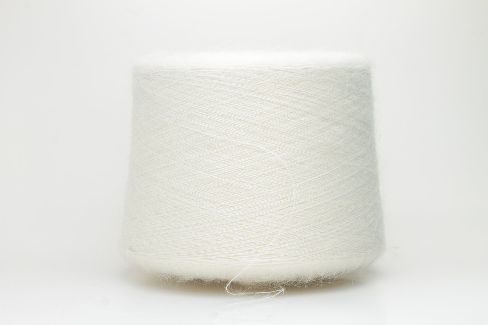 Close-up of pristine white SuperKidMohair Silk yarn, revealing its delicate halo, subtle sheen, and fine, even ply twist.