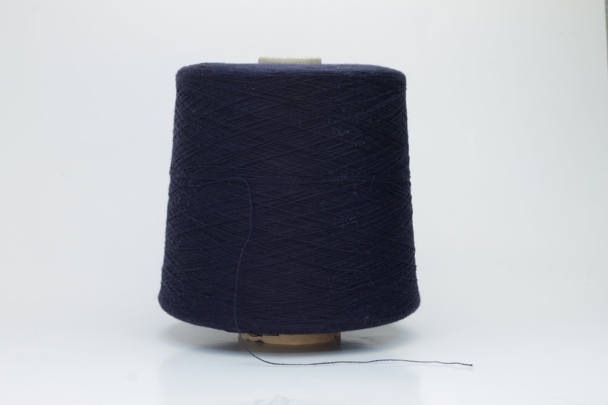 Close-up shot of dark blue, fluffy cotton 85% cashmere 15% yarn in a twisted ply, showcasing the fine thread structure and subtle sheen.