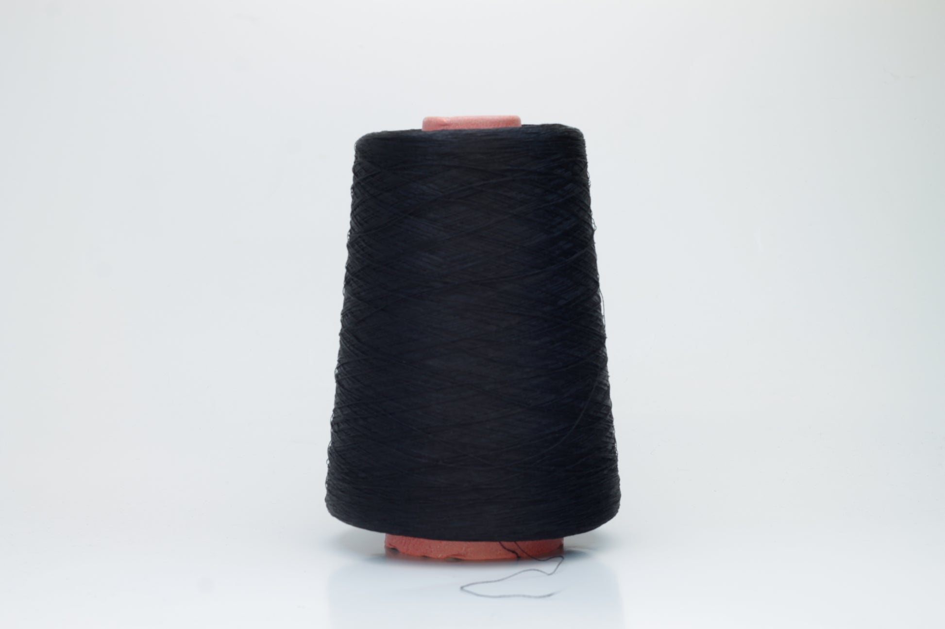 A single, tightly spun strand of incredibly fine, jet black silk yarn, showcasing a brilliant, almost glass-like sheen.