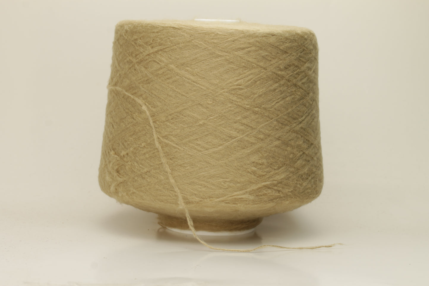 Luxurious, pristine Beige single-ply silk yarn with a smooth, uniform texture and a delicate sheen, softly coiled.