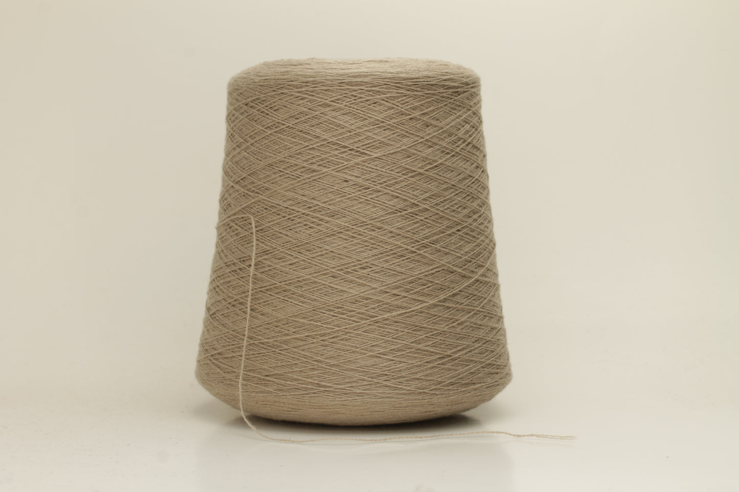 Close-up of a skein of incredibly soft, two-ply cashmere yarn in a deep, warm Mastice beige. Fine fibers with a subtle halo and elegant twist visible.