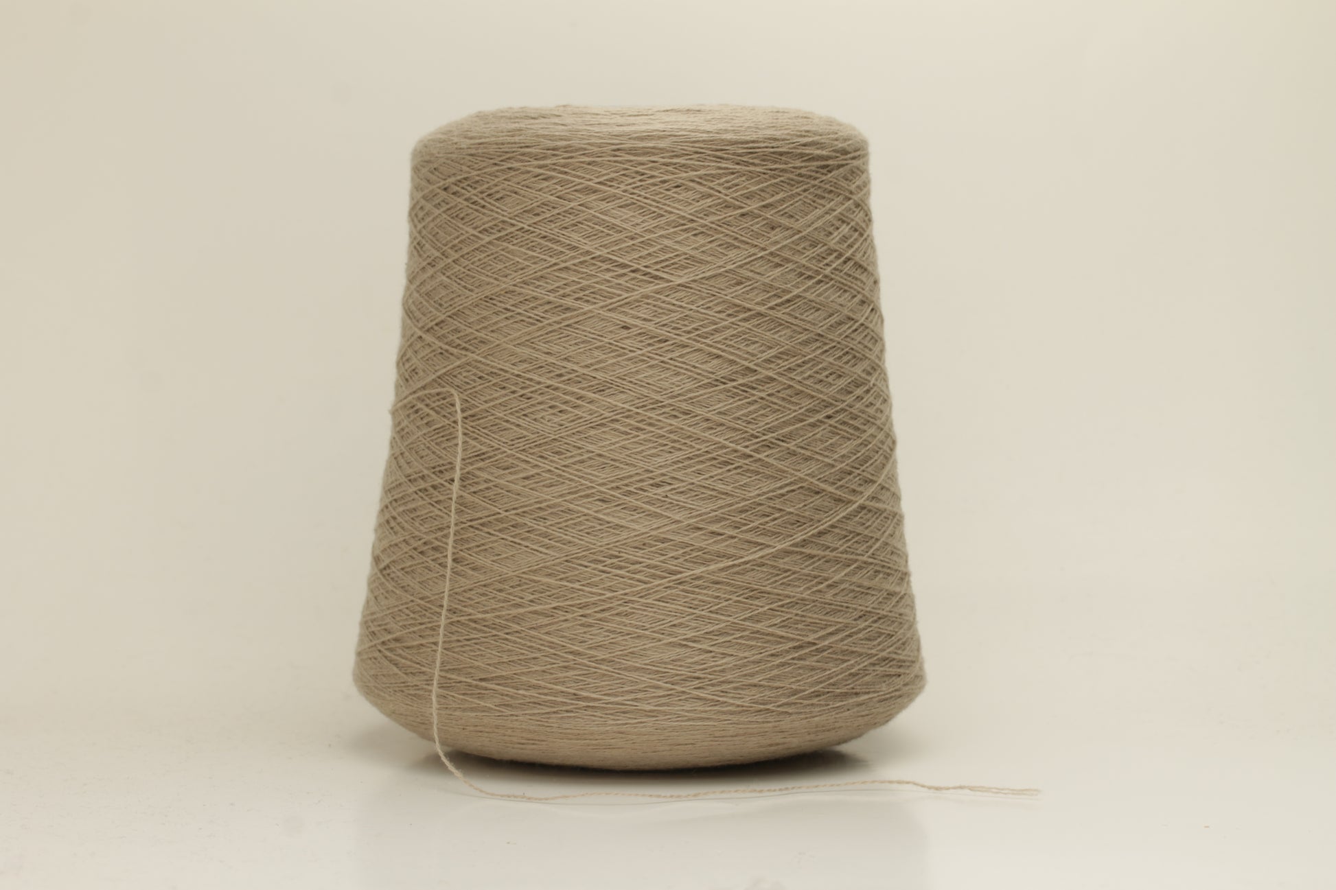 Close-up of a skein of incredibly soft, two-ply cashmere yarn in a deep, warm Mastice beige. Fine fibers with a subtle halo and elegant twist visible.