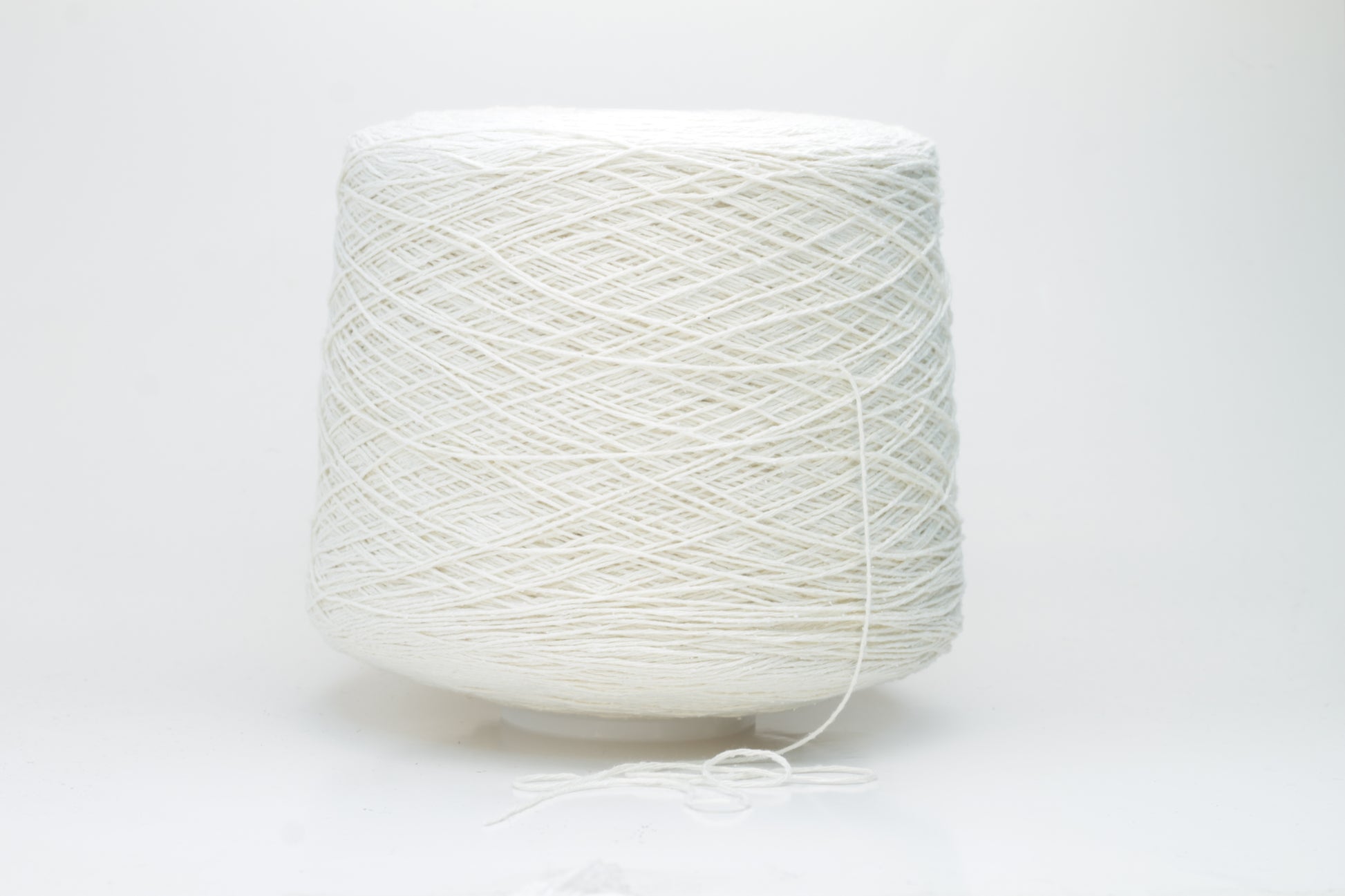 Close-up shot showcasing the fluffy, lustrous sheen of white silk bourette yarn in a single ply twist. The thread structure is clearly visible with subtle variations in color depth.