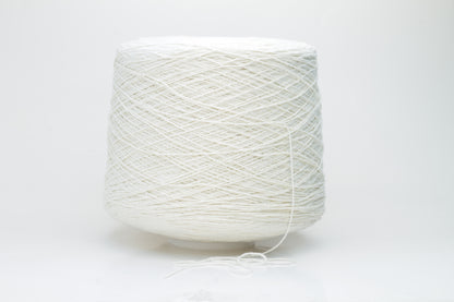 Close-up shot showcasing the fluffy, lustrous sheen of white silk bourette yarn in a single ply twist. The thread structure is clearly visible with subtle variations in color depth.