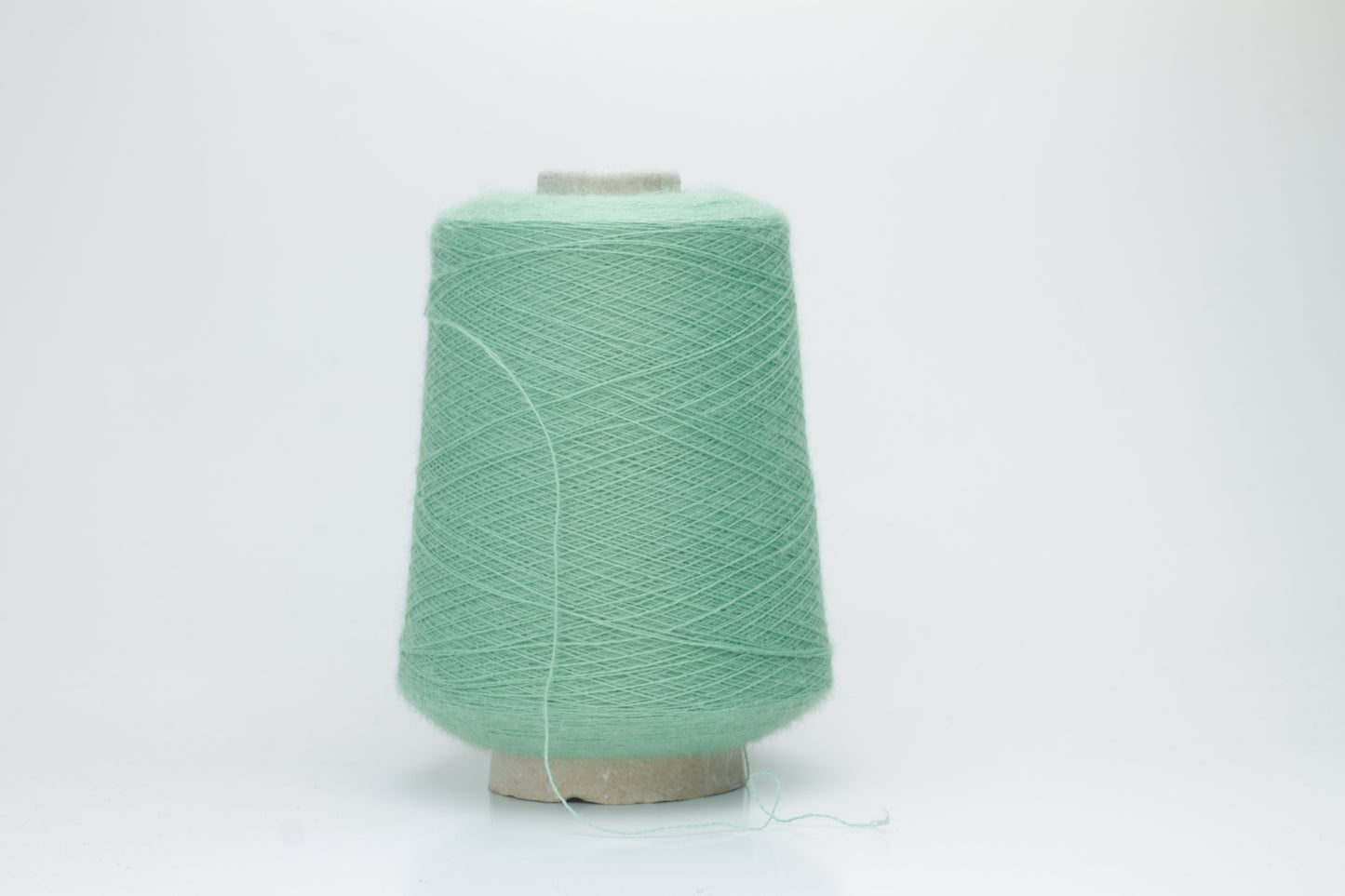 Close-up of a skein of soft, plied alpaca merino yarn in a deep green, showing subtle sheen and fine fiber halo.