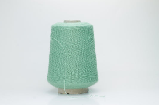 Close-up of a skein of soft, plied alpaca merino yarn in a deep green, showing subtle sheen and fine fiber halo.