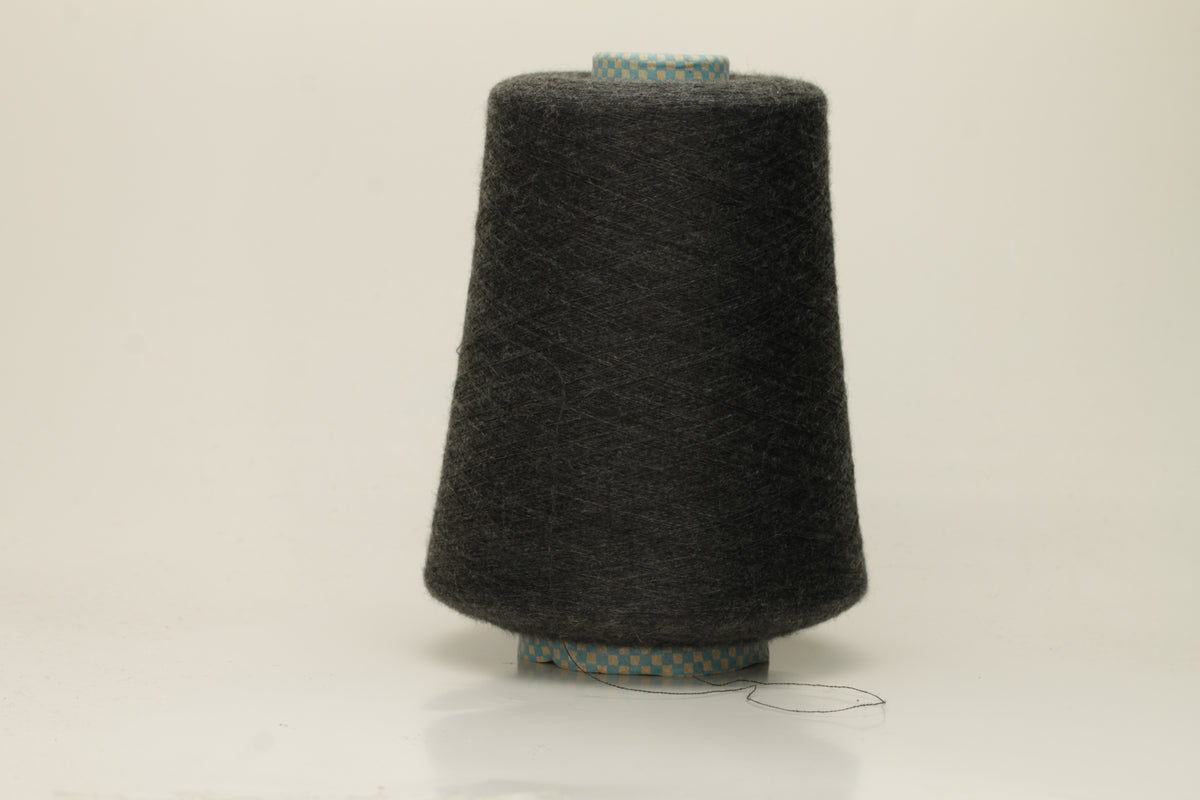 Close-up of a luxurious, finely spun two-ply cashmere silk blend yarn in a soft, elegant gray shade with a subtle sheen, showcasing its delicate texture.