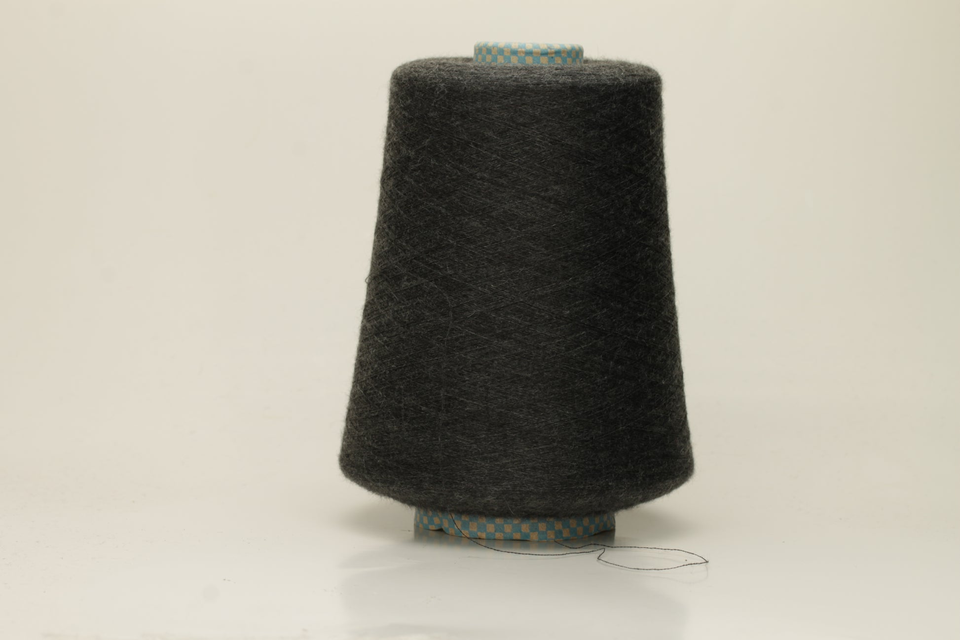 Close-up of a luxurious, finely spun two-ply cashmere silk blend yarn in a soft, elegant gray shade with a subtle sheen, showcasing its delicate texture.