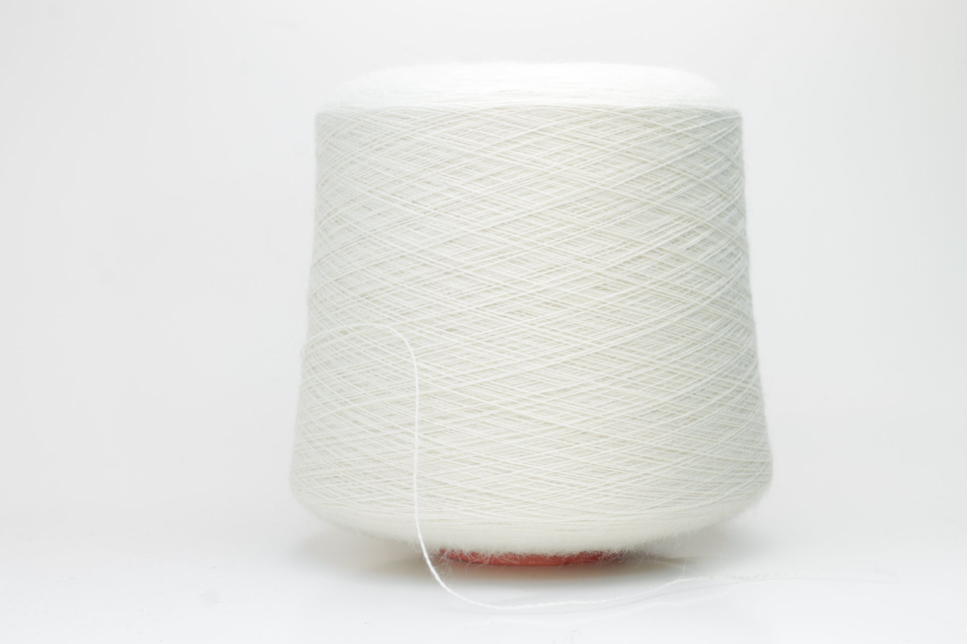 A close-up shot of a single ply, pure white alpaca yarn, softly twisted, showcasing its ethereal fluffiness and subtle sheen against a neutral background.