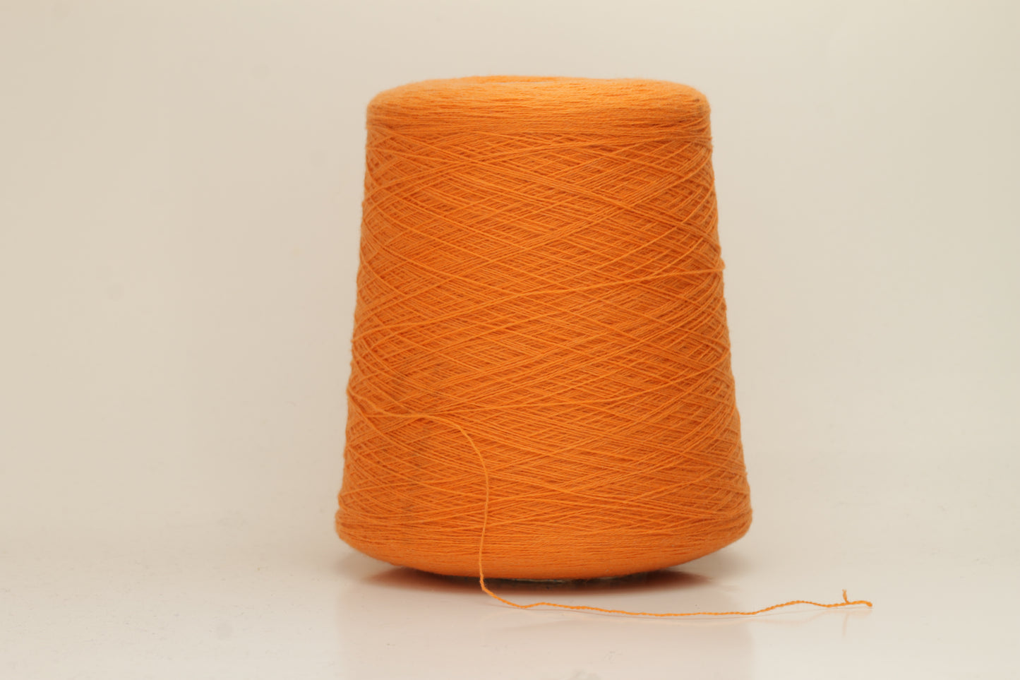 Close-up of fluffy, deeply saturated Jaffa orange cashmere yarn, showing its soft, slightly twisted two-ply structure and delicate sheen.