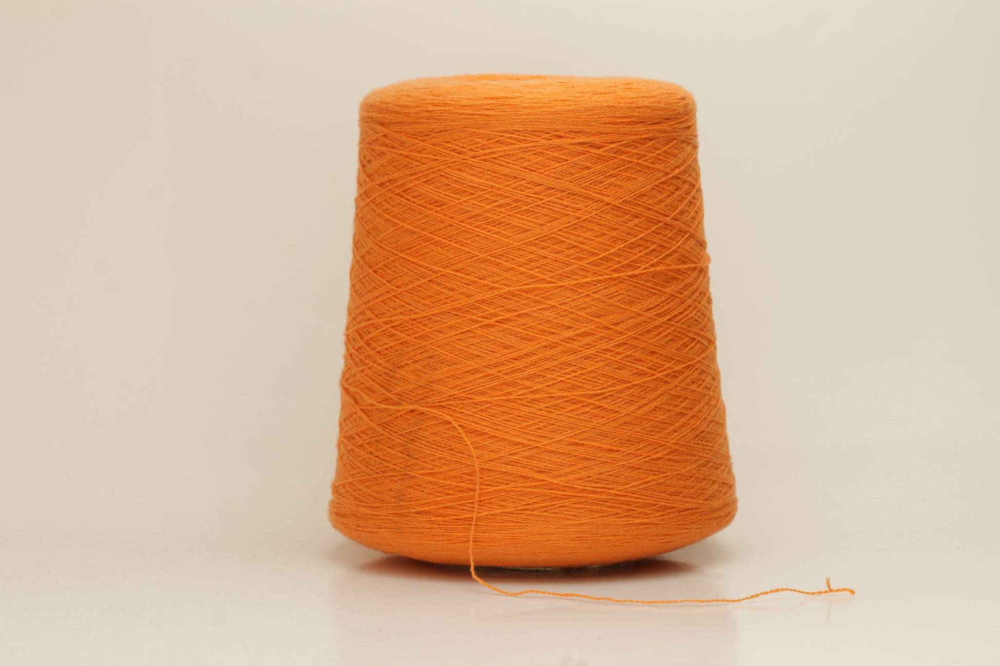 Close-up of fluffy, deeply saturated Jaffa orange cashmere yarn, showing its soft, slightly twisted two-ply structure and delicate sheen.