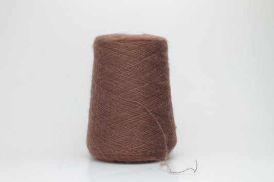 Close-up of fluffy Marrone kid mohair and silk blend yarn, subtly lustrous with a soft halo, gently twisted into a fine, delicate thread.